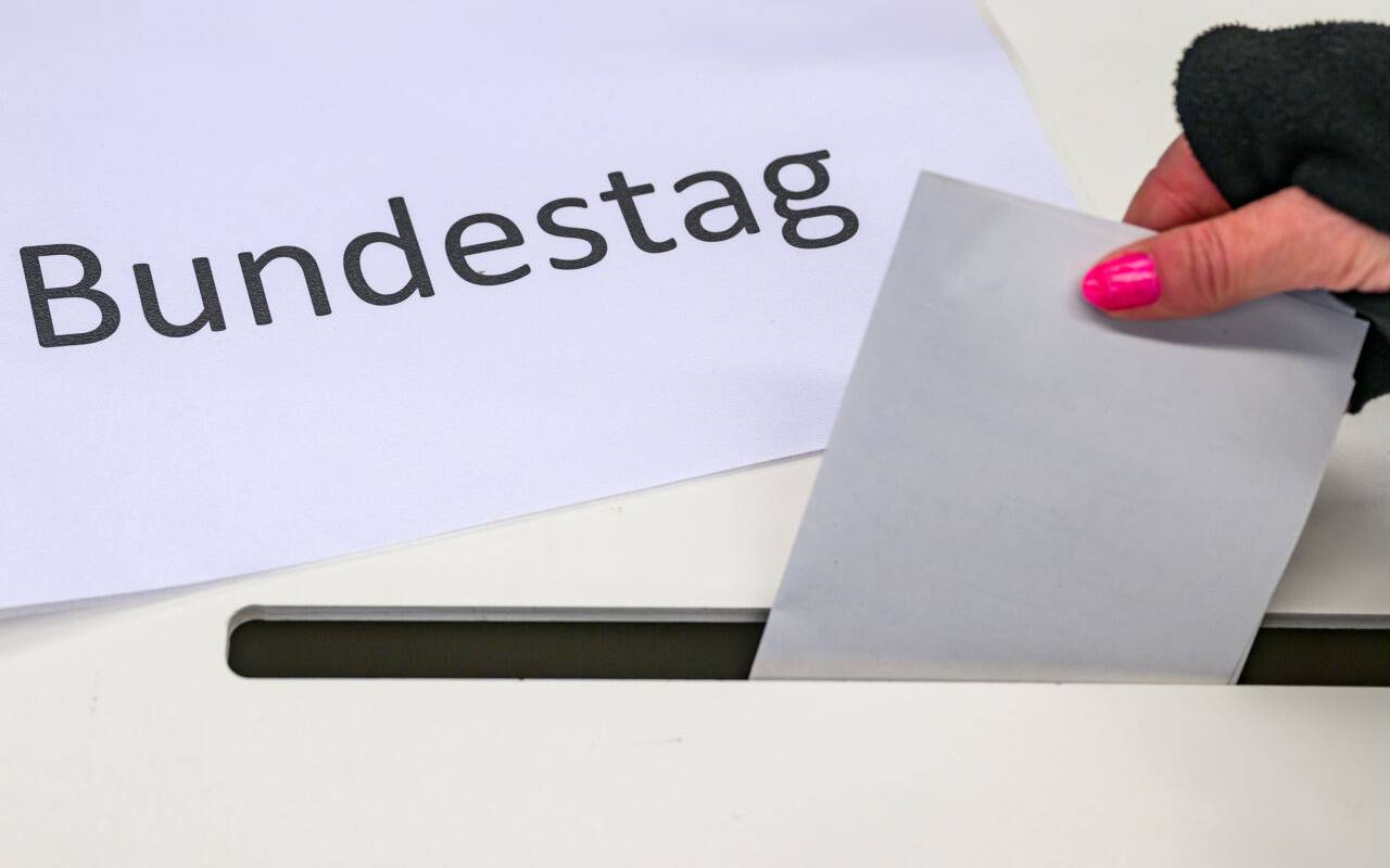 Eine Wählerin wirft in einem Wahllokal ihren Stimmzettel in eine Wahlurne, auf der ein Zettel mit der Aufschrift "Bundestag" liegt.