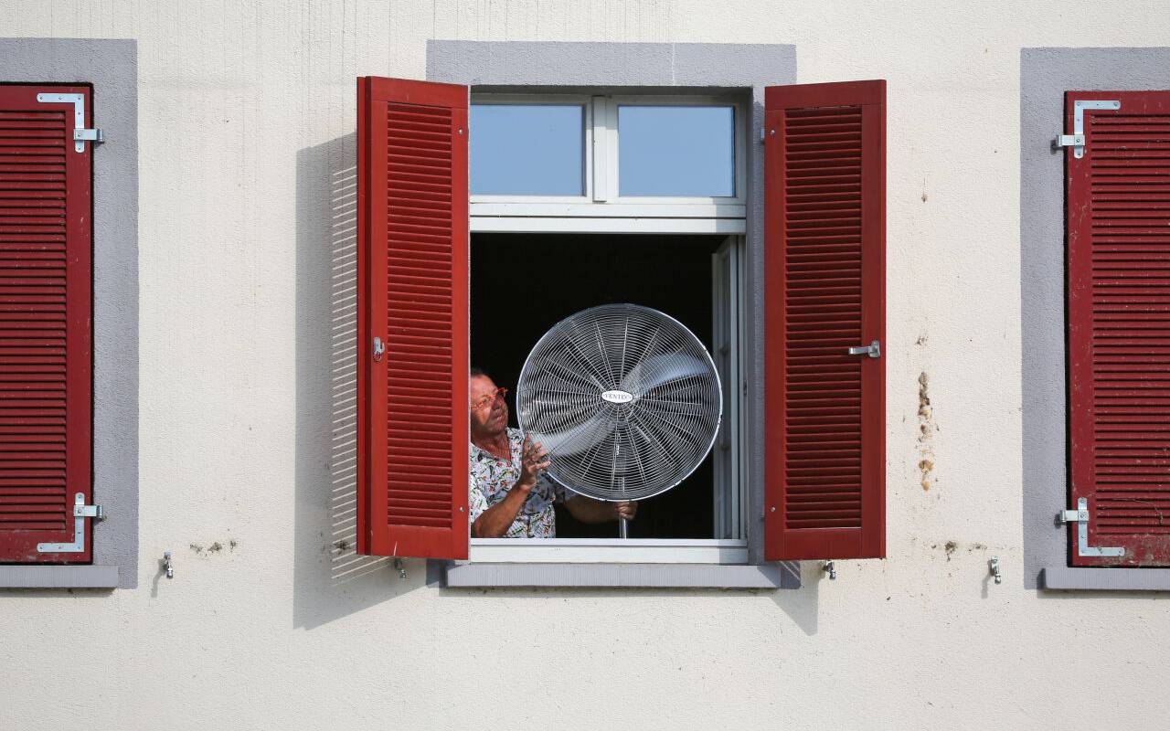 Ein Mann stellt am Morgen einen Ventilator an sein geöffnetes Fenster. Für viele Tage im Sommer sind Temperaturen über 30 Grad Celsius vorhergesagt.