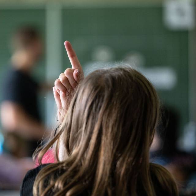 Schülerinnen und Schüler einer vierten Klasse einer Grundschule nehmen am Unterricht teil, eine Schülerin meldet sich.