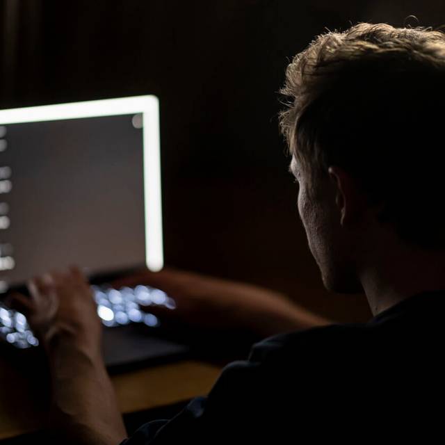 Ein Mann schreibt auf der Tastatur eines Laptops.