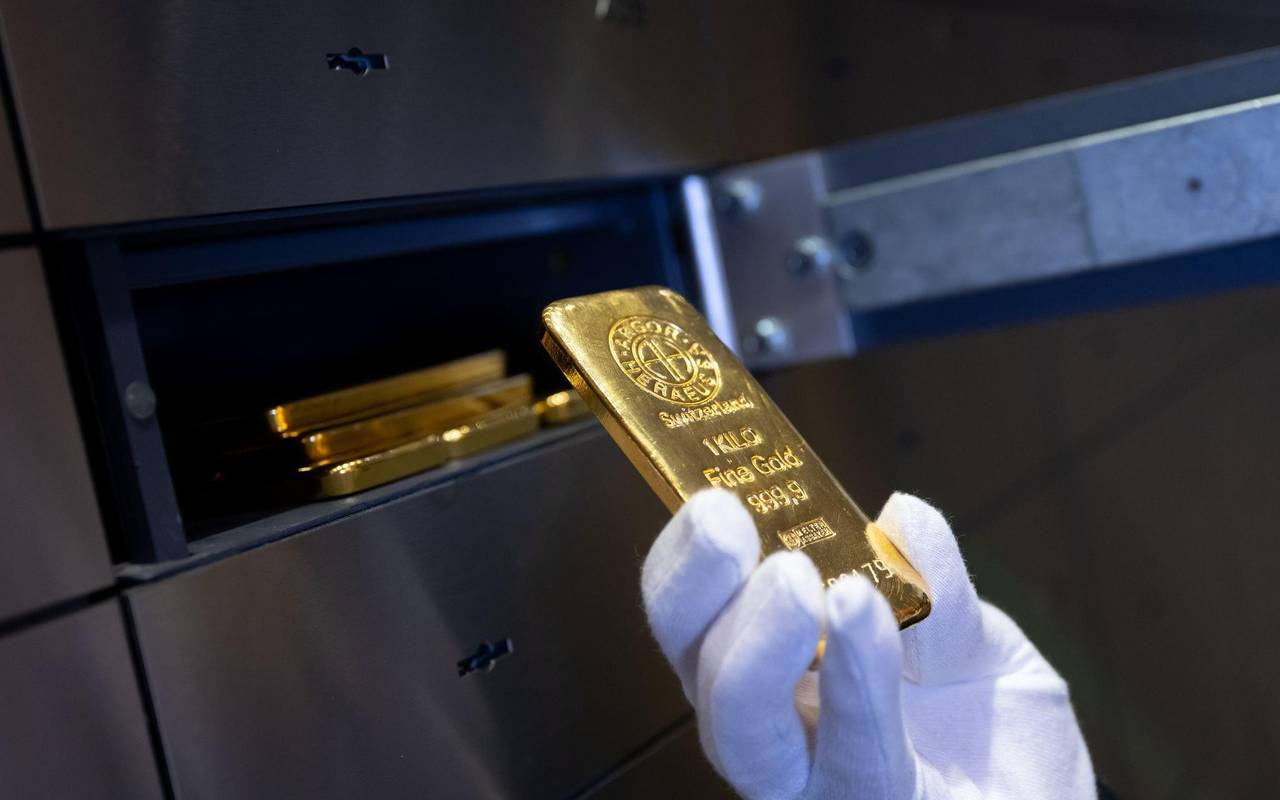 Mann legt einen Goldbarren in ein Schließfach eines Tresorraums